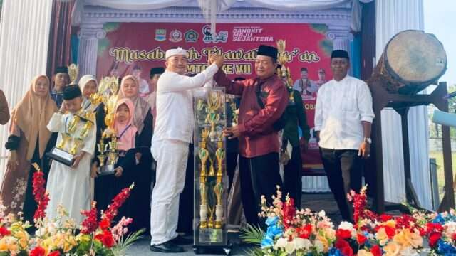 Camat Sukawangi Parno Martono, menyerahkan tropi juara umum MTQ kepada Kepala Desa Sukamekar.