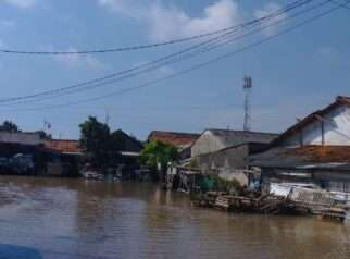 Luapan Kali Cikarang Bekasi Laut lumpuhkan akses jalan. Warga gunakan gerobak untuk bantu sesama melintas genangan.